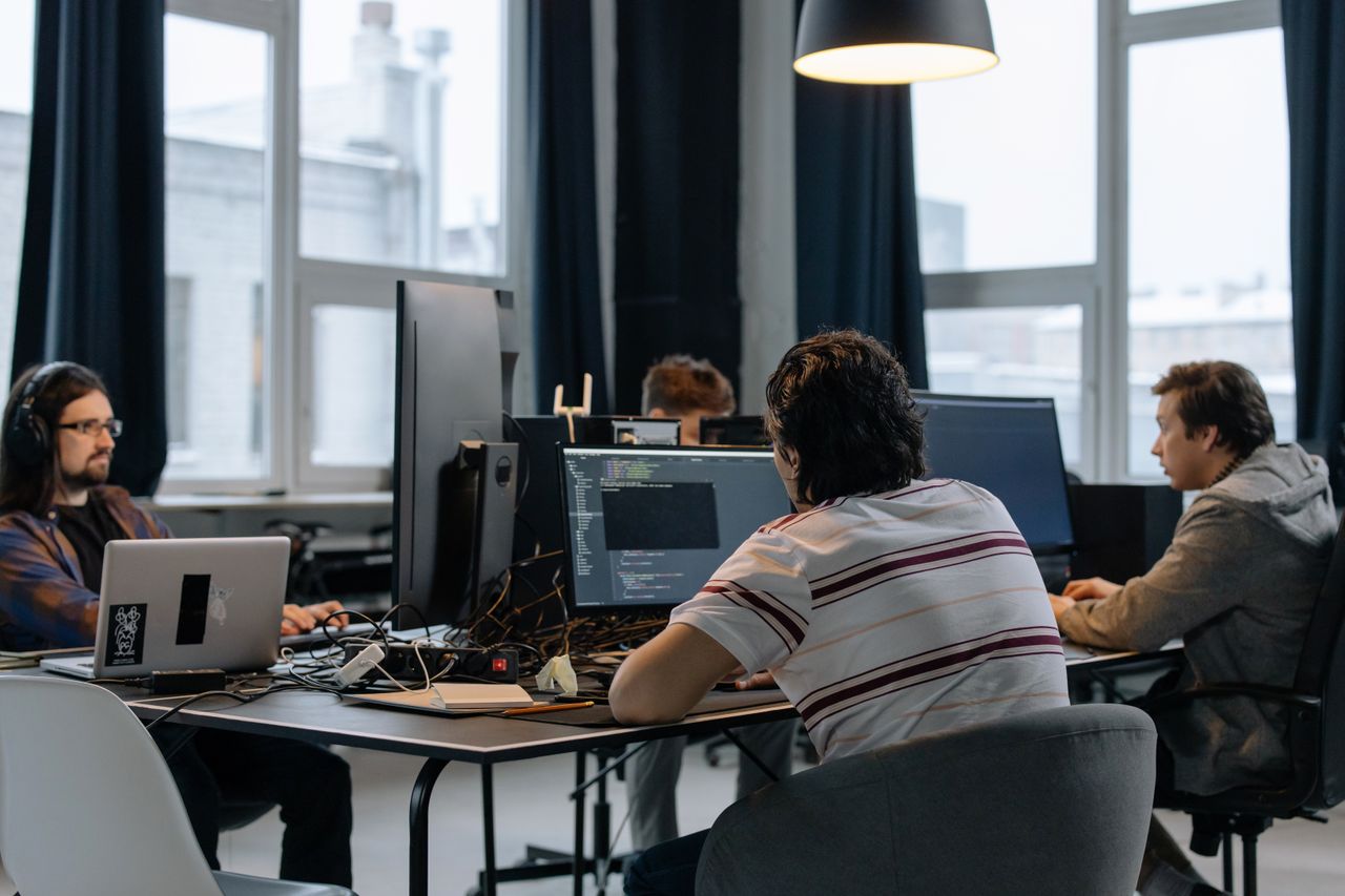 about-us Team of developers working together on computers in a modern tech office.